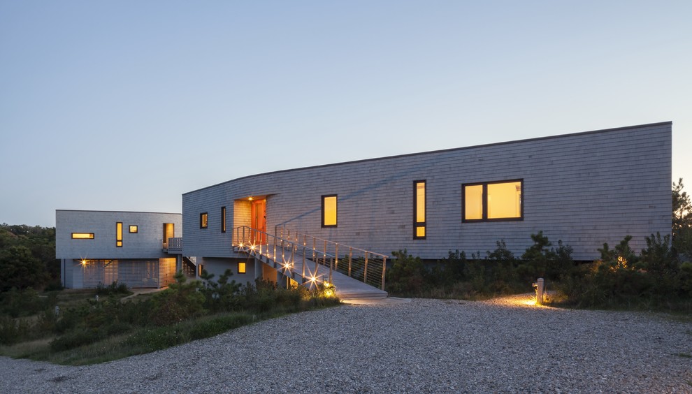 Cette image montre une façade de maison grise design en bois à un étage avec un toit plat.