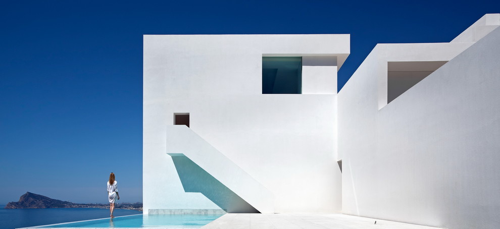 Пример оригинального дизайна: трехэтажный, белый дом в современном стиле с облицовкой из бетона и плоской крышей