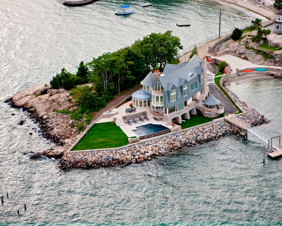 На фото: огромный, деревянный, синий частный загородный дом в морском стиле с разными уровнями, двускатной крышей и крышей из гибкой черепицы с