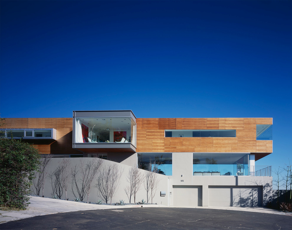Cette photo montre une très grande façade de maison beige tendance en bois à niveaux décalés avec un toit plat.