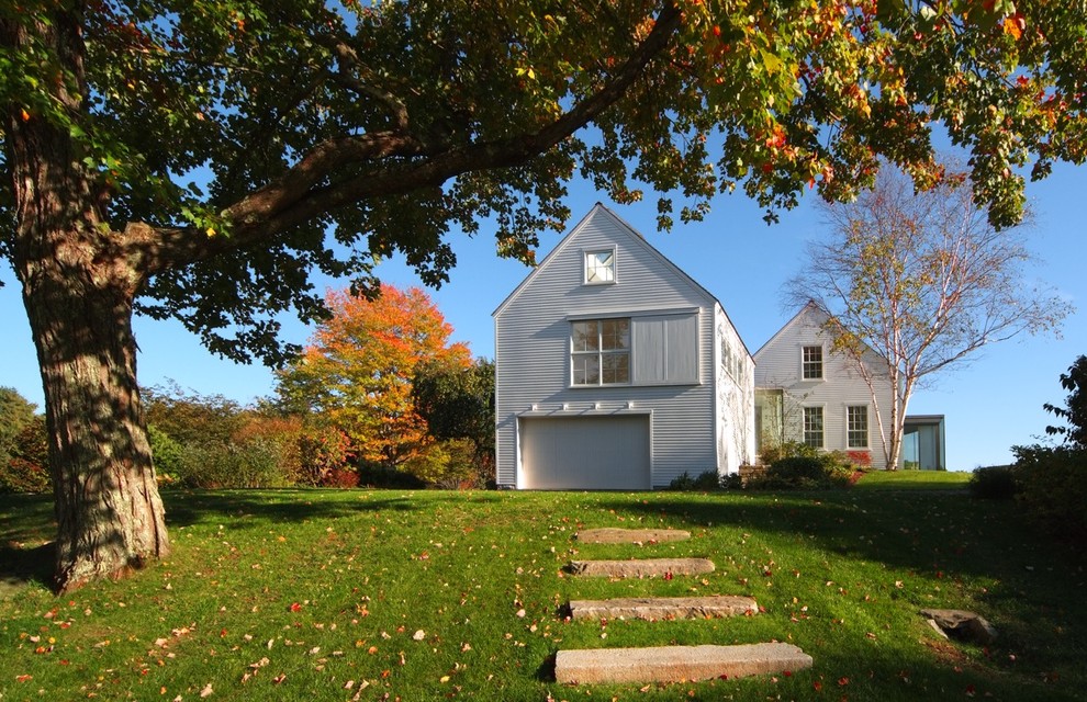 На фото: двухэтажный, деревянный, белый дом в стиле кантри с двускатной крышей с