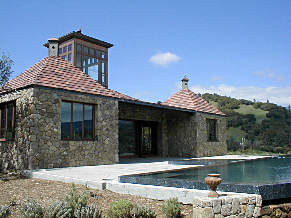 Foto de fachada actual pequeña de dos plantas con revestimiento de piedra y tejado a cuatro aguas