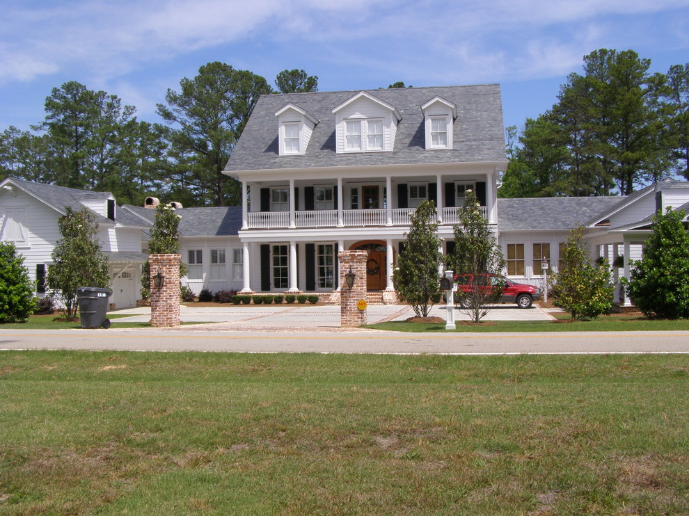 Immagine della facciata di una casa grande bianca moderna a tre piani con rivestimento in legno e tetto a capanna