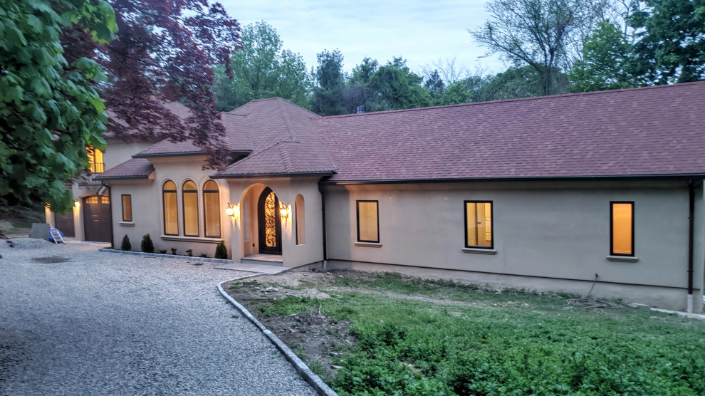 Modelo de fachada de casa beige mediterránea de tamaño medio de una planta con revestimiento de estuco y tejado a cuatro aguas