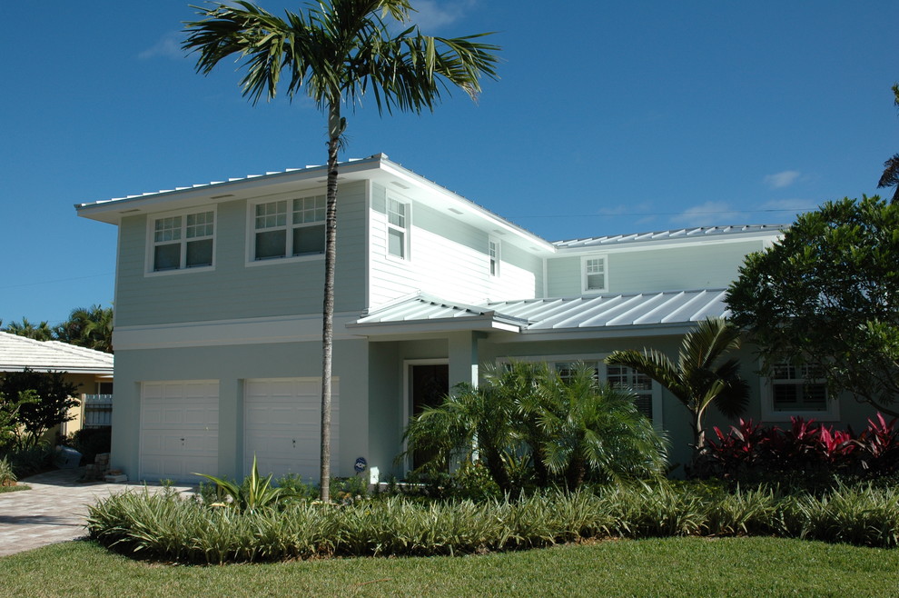 Imagen de fachada de casa tropical de tamaño medio de dos plantas con revestimiento de aglomerado de cemento, tejado a cuatro aguas y tejado de metal