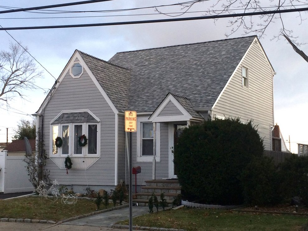 Imagen de fachada de casa gris moderna de tamaño medio de dos plantas con revestimiento de vinilo, tejado a dos aguas y tejado de teja de madera