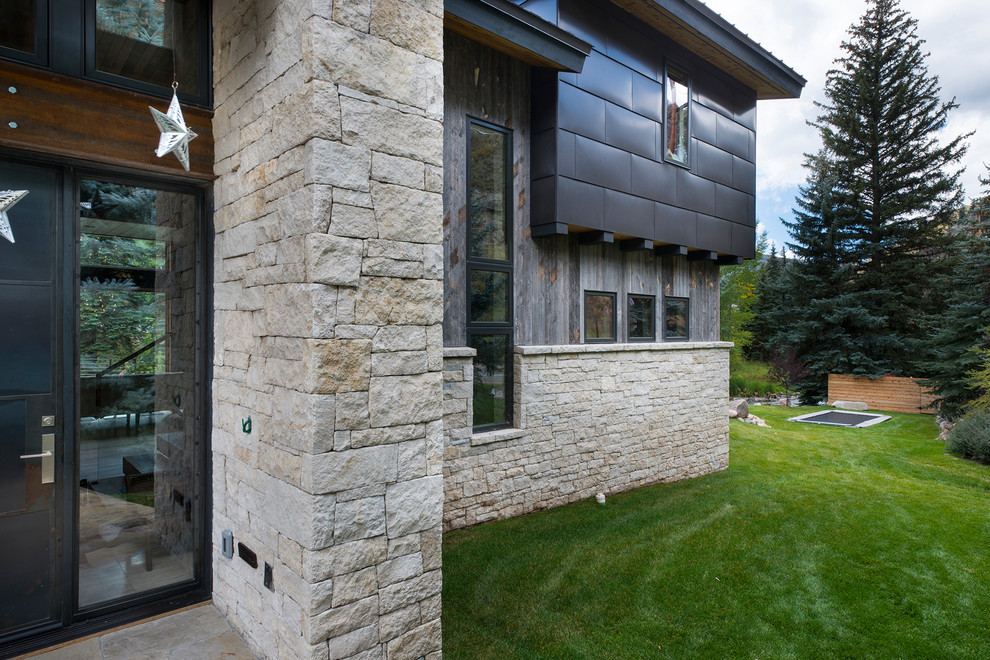 Cette image montre une façade de maison grise design en pierre de taille moyenne et à un étage avec un toit à deux pans.