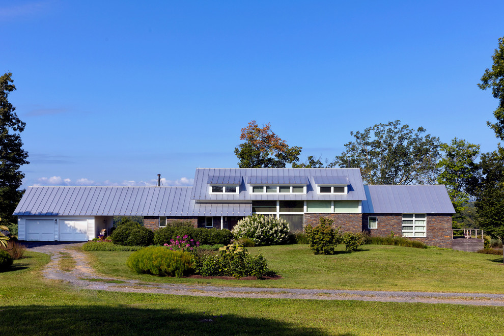 Imagen de fachada de casa multicolor actual de tamaño medio de dos plantas con revestimiento de piedra, tejado de un solo tendido y tejado de metal