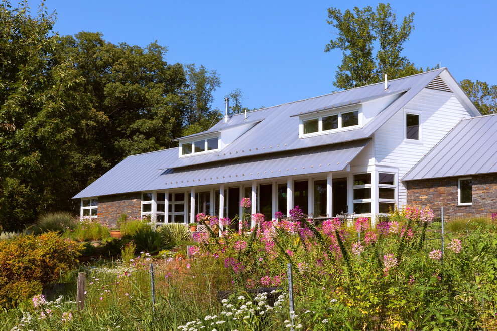 Imagen de fachada de casa multicolor contemporánea de tamaño medio de dos plantas con revestimiento de piedra, tejado de un solo tendido y tejado de metal