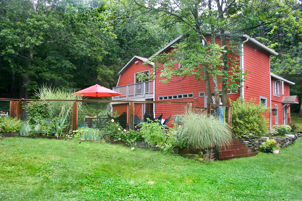 Ejemplo de fachada roja moderna grande de dos plantas con revestimiento de madera y tejado a cuatro aguas