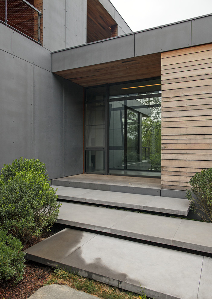 На фото: большой, двухэтажный, серый частный загородный дом в стиле модернизм с облицовкой из бетона, плоской крышей и зеленой крышей