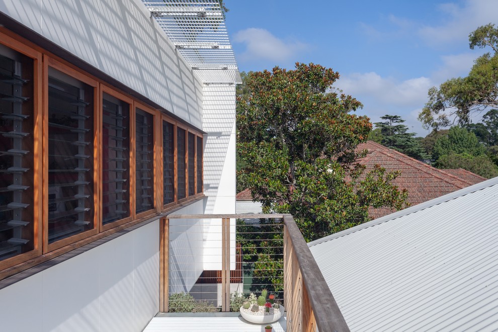 This is an example of a medium sized and white contemporary two floor detached house in Sydney with concrete fibreboard cladding, a flat roof and a metal roof.