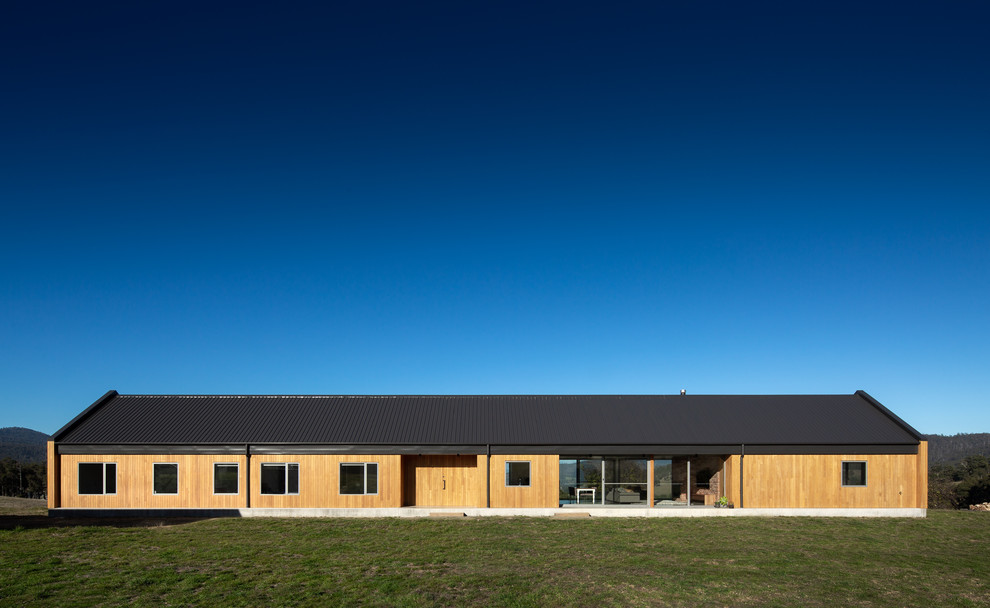Cette image montre une grande façade de maison beige rustique en bois de plain-pied avec un toit à deux pans et un toit en métal.