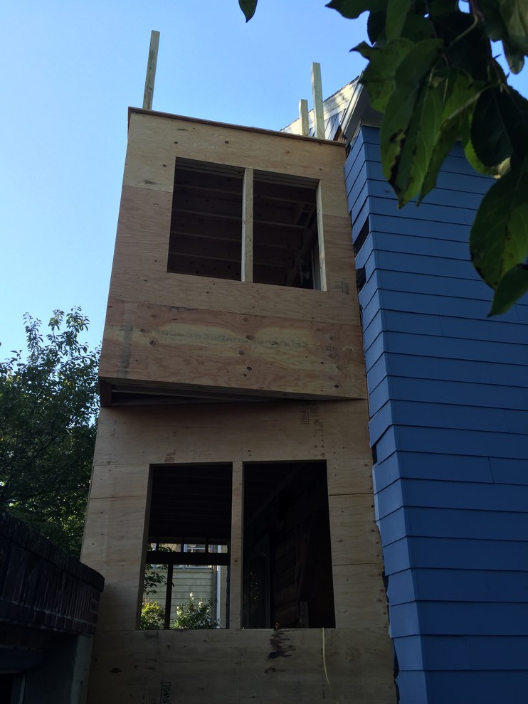 Ejemplo de fachada gris tradicional de tamaño medio de tres plantas con revestimiento de madera y tejado plano
