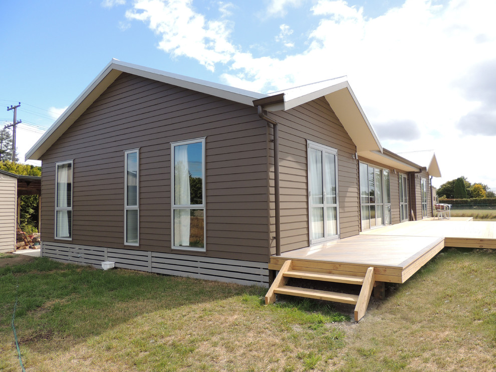 Exempel på ett stort modernt brunt hus, med allt i ett plan, fiberplattor i betong och sadeltak
