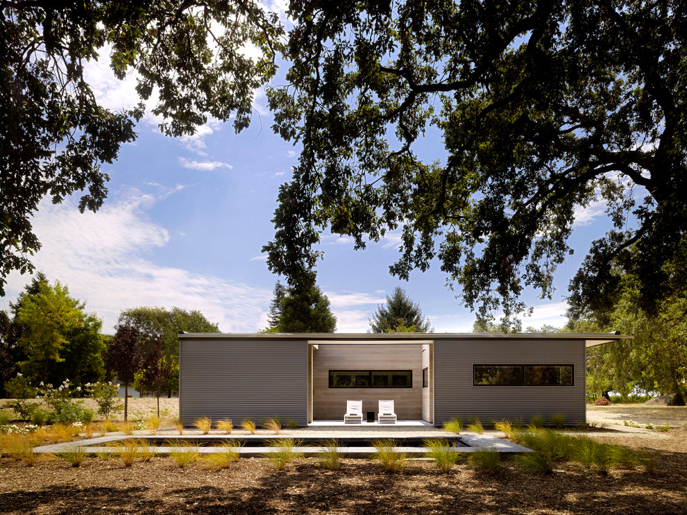 Ispirazione per la facciata di una casa piccola grigia moderna a un piano con rivestimento in metallo e tetto piano