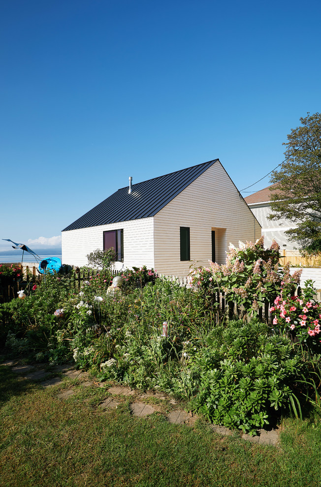 Diseño de fachada de casa blanca escandinava pequeña de una planta con revestimiento de madera, tejado a dos aguas y tejado de metal