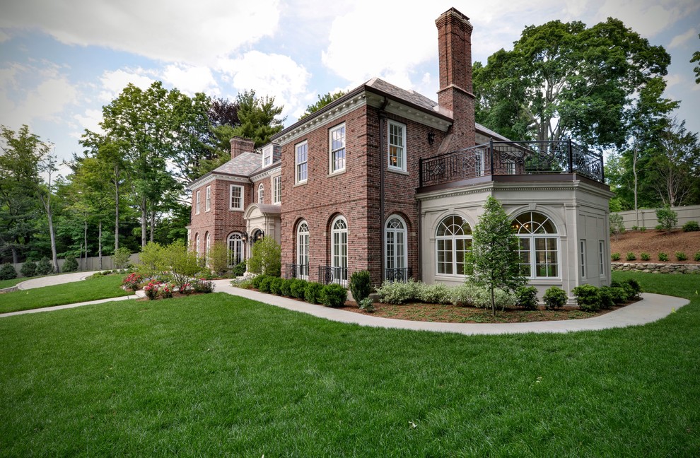 This is an example of an expansive and red traditional two floor brick house exterior in Boston with a hip roof.