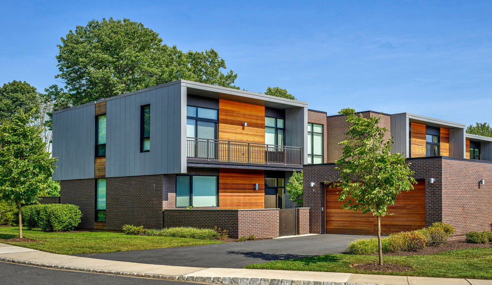 Immagine della facciata di una casa a schiera marrone moderna a due piani di medie dimensioni con rivestimento in legno, tetto piano, copertura mista, tetto grigio e pannelli sovrapposti