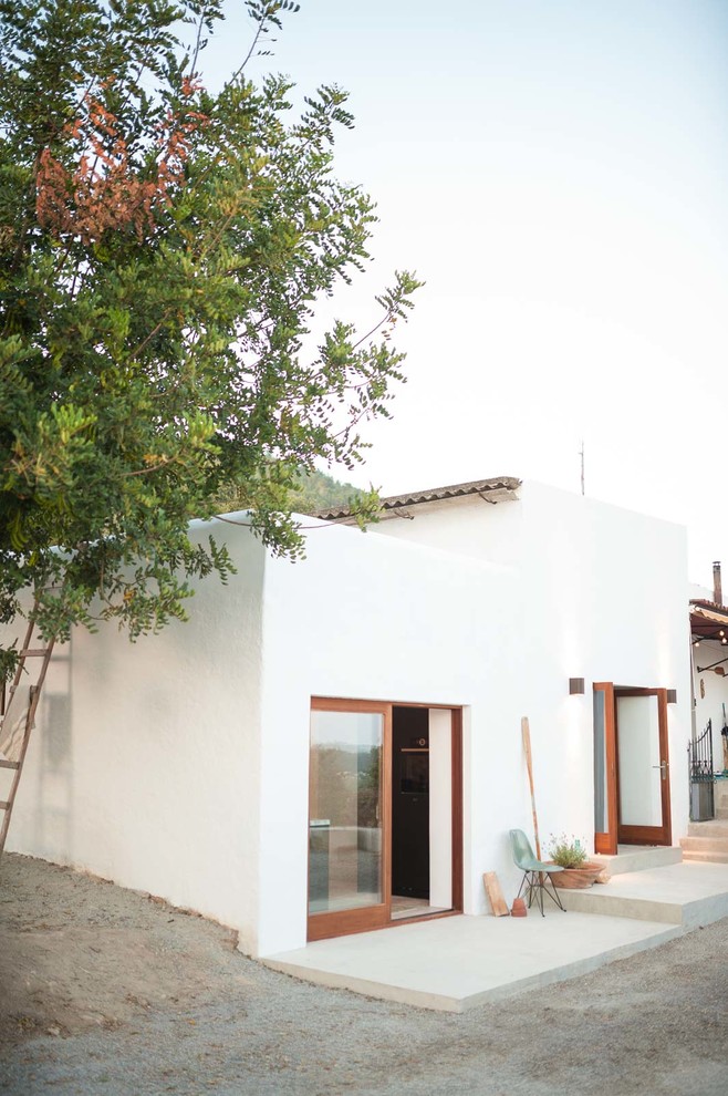 Cette image montre une façade de maison blanche méditerranéenne de taille moyenne et à un étage avec un revêtement mixte et un toit plat.