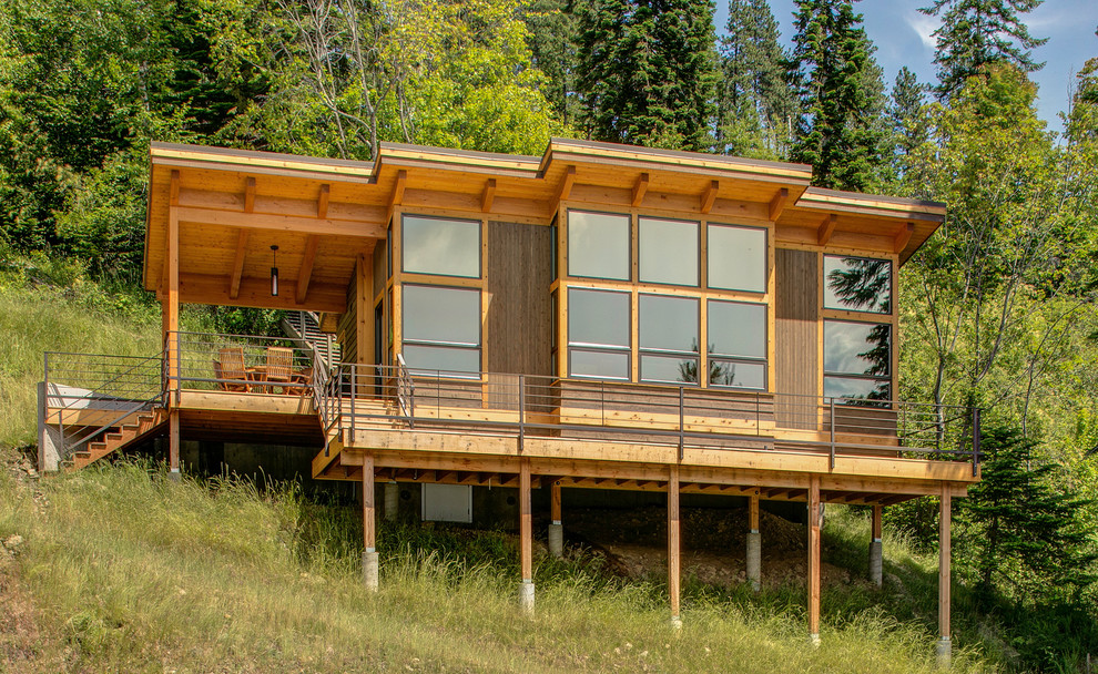 Idee per la facciata di una casa marrone rustica a due piani di medie dimensioni con rivestimento in legno e terreno in pendenza