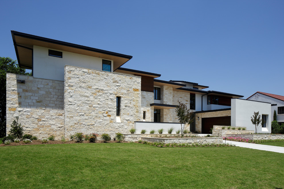 Large and beige modern two floor house exterior in Dallas with stone cladding and a flat roof.