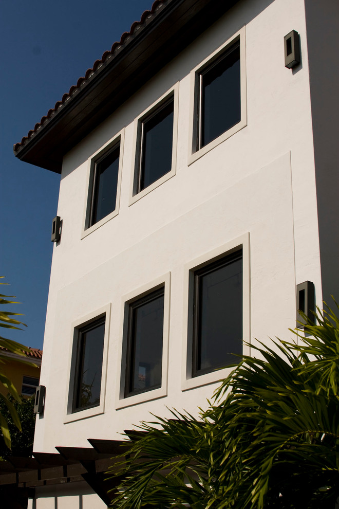 Imagen de fachada blanca tropical grande de dos plantas con revestimiento de hormigón y tejado a dos aguas