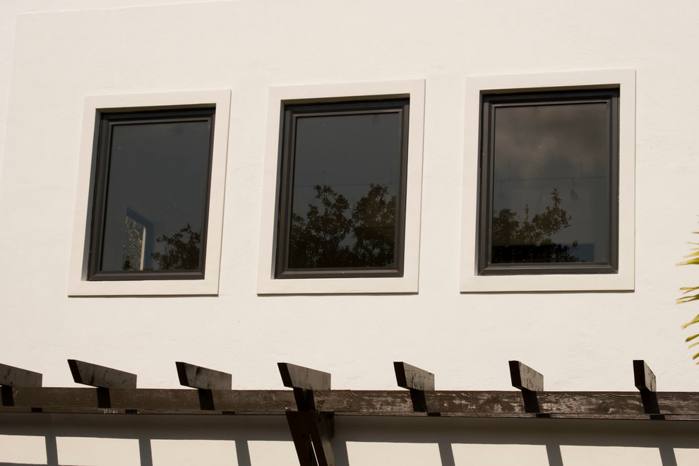 Cette photo montre une façade de maison blanche moderne en béton à un étage avec un toit à deux pans.