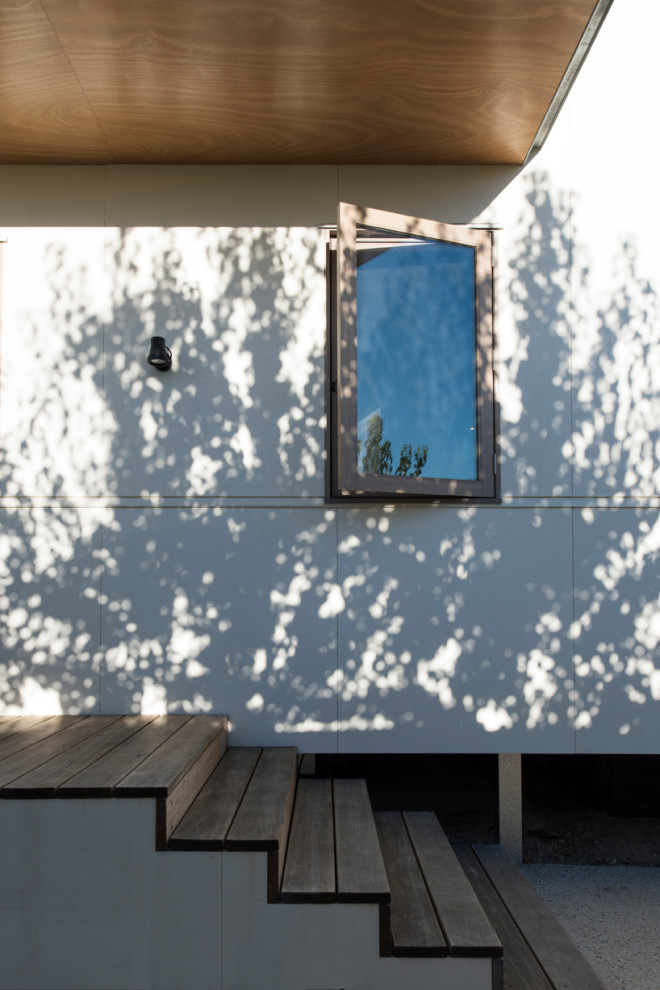 Ejemplo de fachada de casa blanca moderna de tamaño medio de una planta con revestimiento de madera, tejado plano y tejado de metal