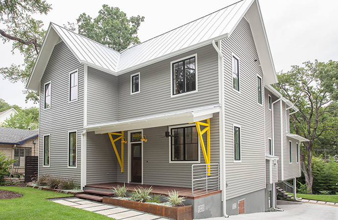 Modelo de fachada gris campestre de tamaño medio de dos plantas con revestimiento de aglomerado de cemento y tejado a dos aguas