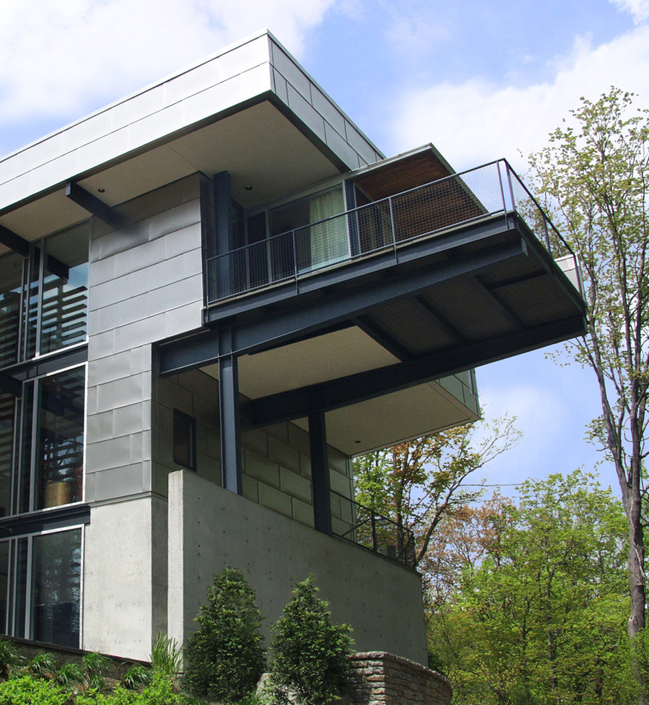 Ejemplo de fachada de casa gris actual grande de tres plantas con revestimiento de metal y tejado plano