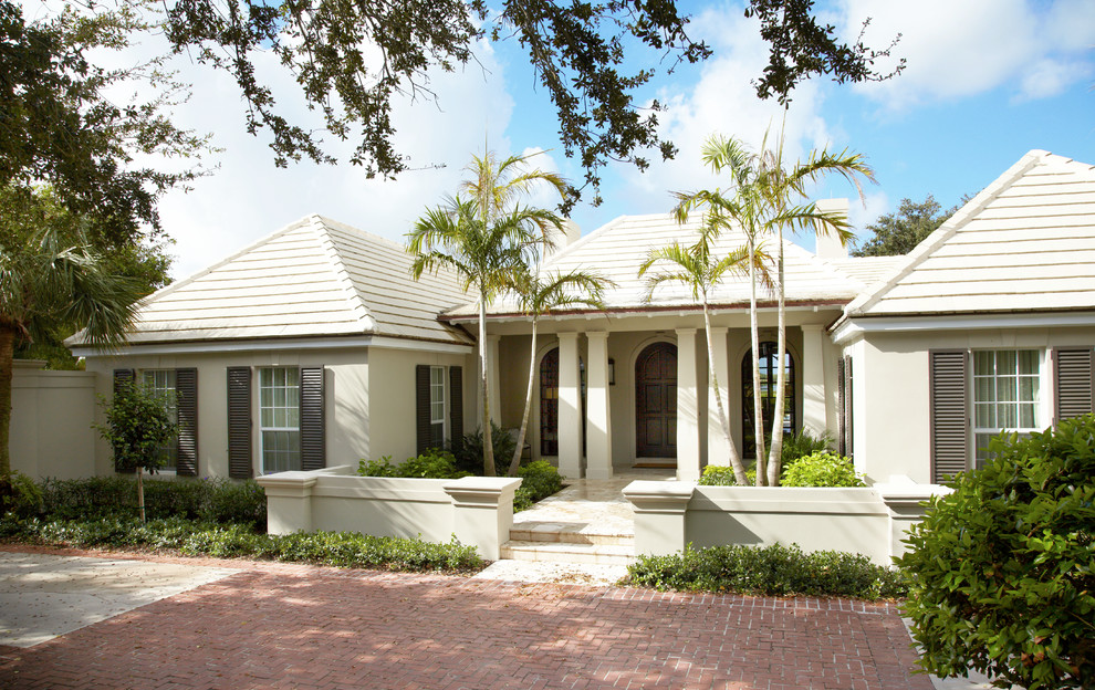 Photo of a large and beige coastal bungalow render house exterior in Miami.