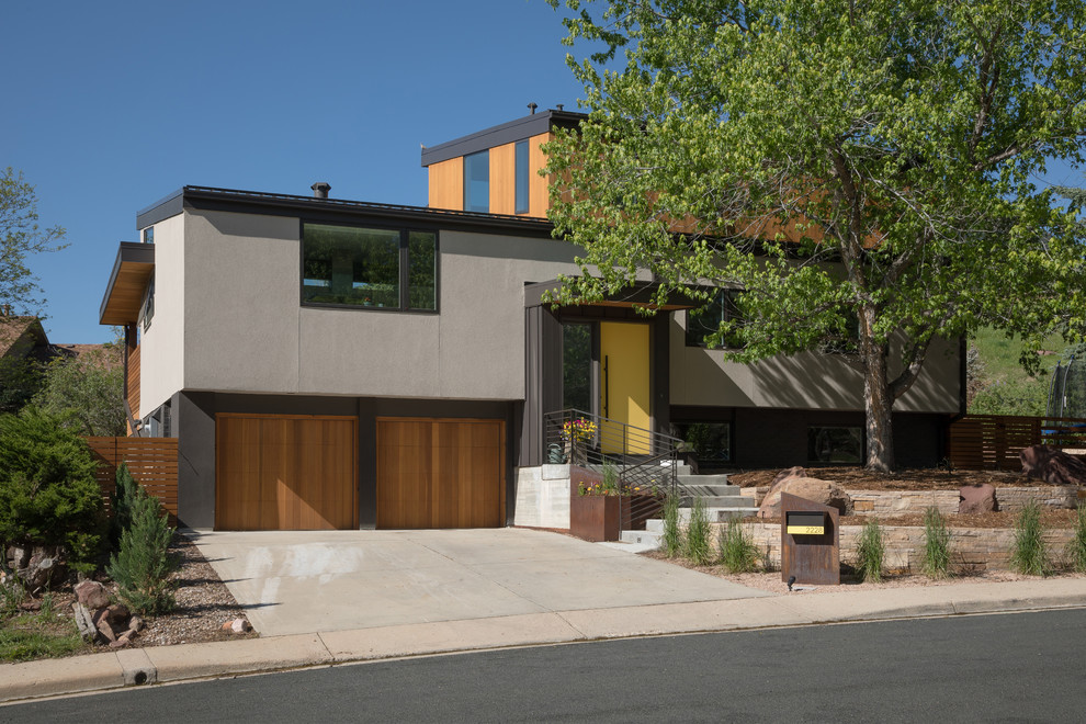 Diseño de fachada de casa gris actual a niveles con revestimientos combinados y tejado de un solo tendido