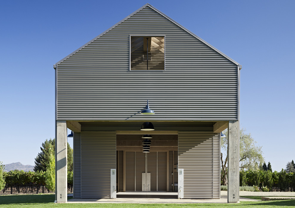 Inspiration för ett industriellt grått hus, med två våningar, metallfasad och sadeltak