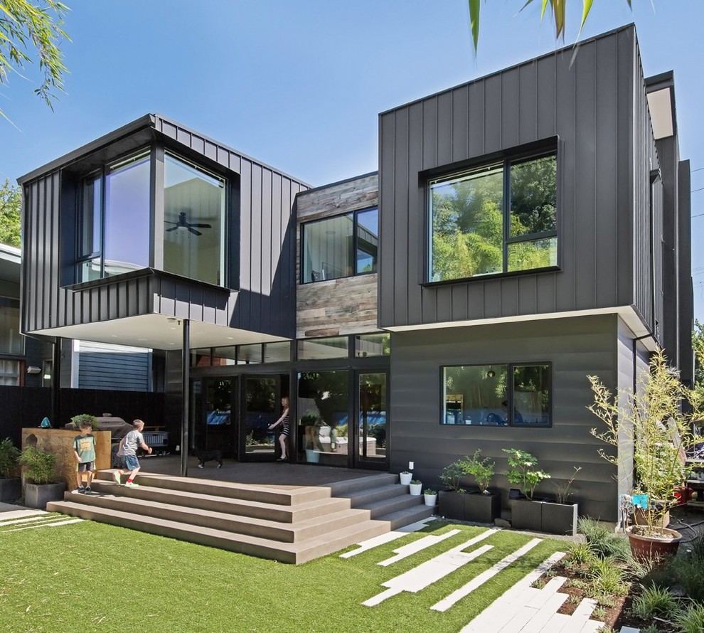 Cette photo montre une façade de maison métallique et noire moderne à deux étages et plus avec un toit plat.