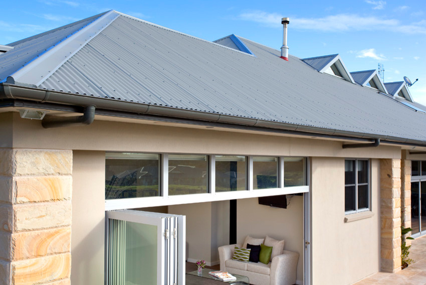 Immagine della villa grande beige country a un piano con tetto a padiglione e copertura in metallo o lamiera