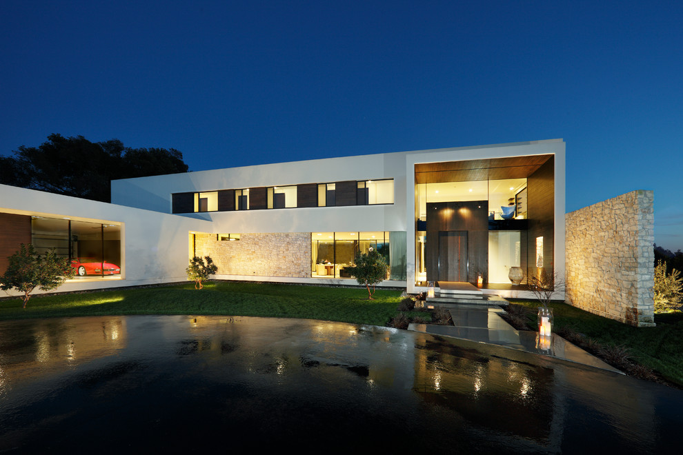 Cette image montre une grande façade de maison blanche minimaliste en verre à un étage.