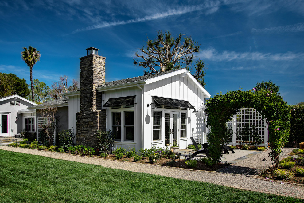Cette image montre une façade de maison blanche rustique de taille moyenne et de plain-pied avec un toit à deux pans et un toit en shingle.