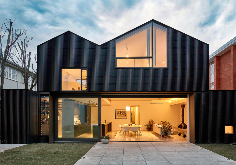 Cette image montre une grande façade de maison noire design à un étage avec un toit à deux pans.