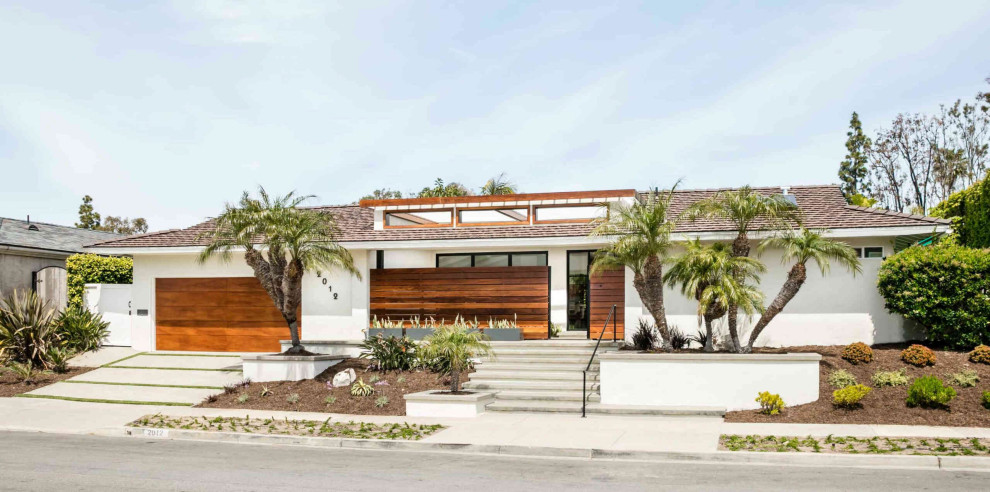 Réalisation d'une très grande façade de maison blanche design de plain-pied avec un toit à quatre pans et un toit marron.