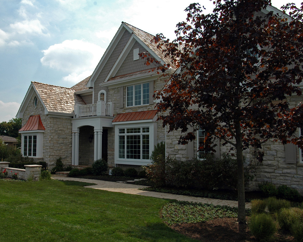 Immagine della facciata di una casa grande beige classica a due piani con rivestimento in pietra e tetto a capanna