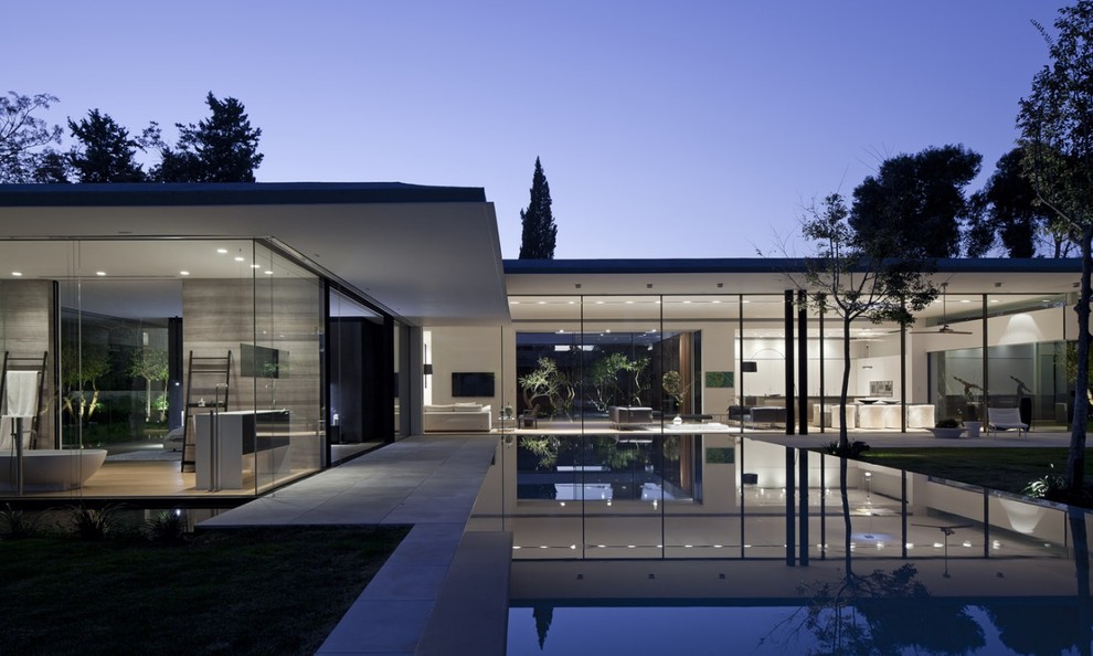 Cette image montre une façade de maison design en verre de plain-pied.