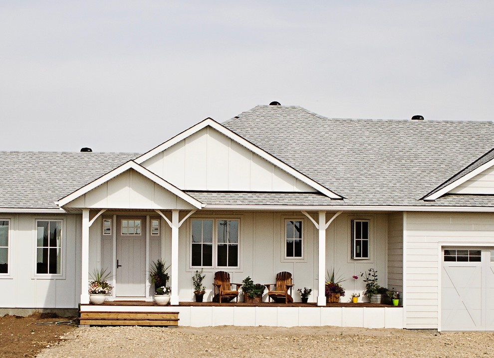 На фото: одноэтажный, белый частный загородный дом в стиле кантри с комбинированной облицовкой, полувальмовой крышей и крышей из гибкой черепицы с