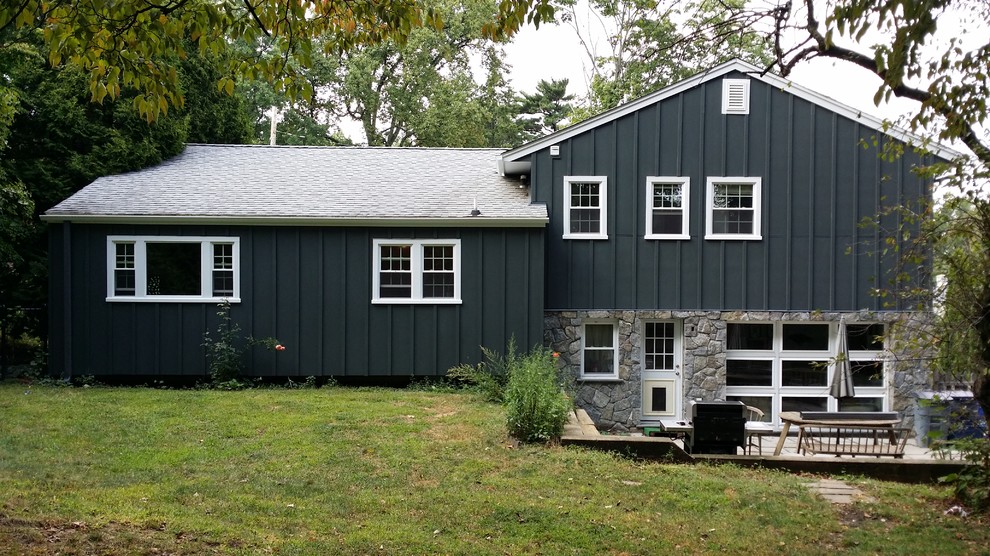 Modelo de fachada de casa azul tradicional de tamaño medio de dos plantas con revestimiento de aglomerado de cemento, tejado a dos aguas y tejado de teja de madera