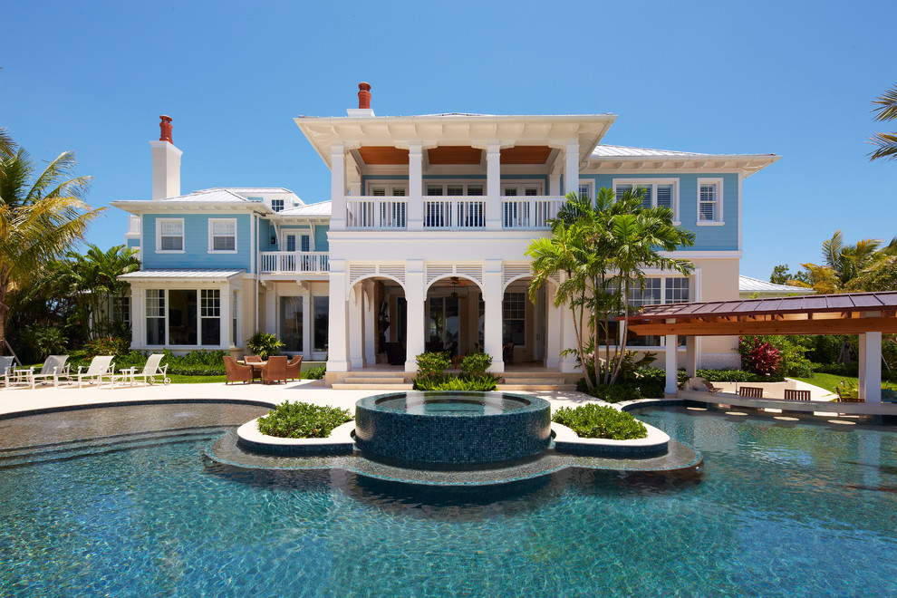 Example of a large island style blue two-story exterior home design in Miami with a hip roof