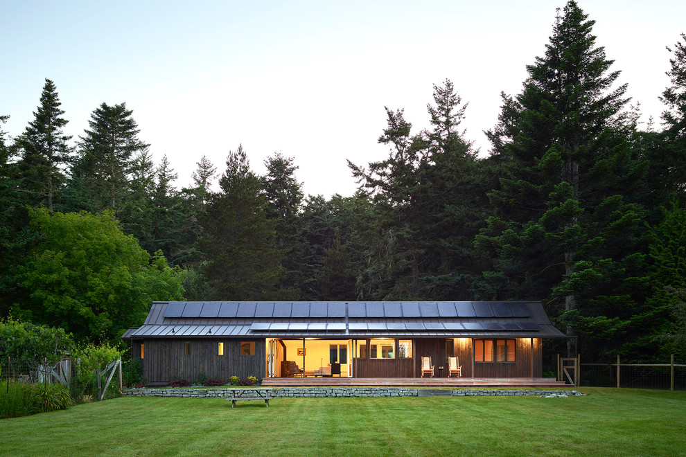 Пример оригинального дизайна: одноэтажный, деревянный, черный частный загородный дом в стиле модернизм с двускатной крышей и металлической крышей для охотников