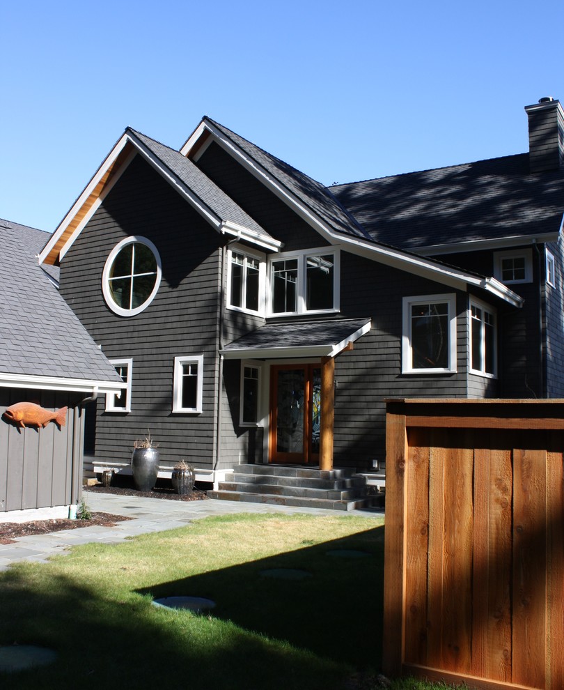 Cette photo montre une façade de maison noire bord de mer en bois de taille moyenne et à un étage avec un toit à deux pans.
