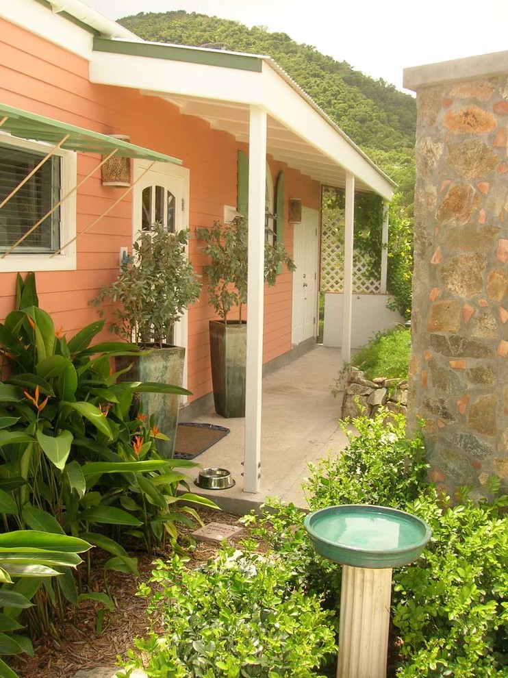 Immagine della facciata di una casa piccola tropicale a un piano con rivestimento con lastre in cemento e tetto a padiglione