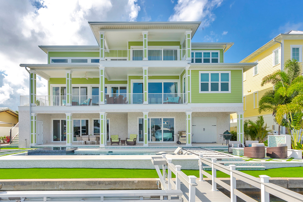 Exemple d'une façade de maison verte bord de mer à deux étages et plus avec un toit plat.