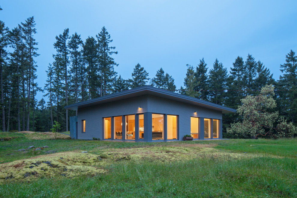 Cette image montre une façade de maison marron design en bois de taille moyenne et de plain-pied avec un toit plat et un toit végétal.